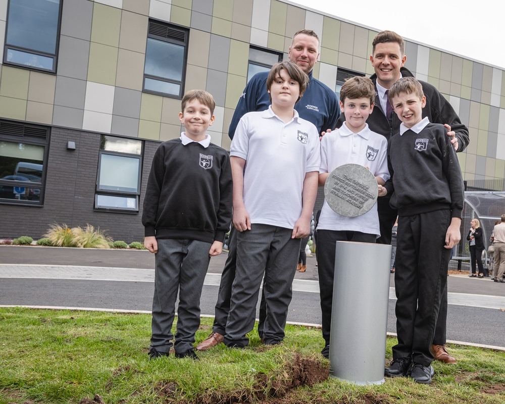 Executive Head, Ashley Caress, with Bowmer Kirkland Project Manager, Shane Jones, bury the time capsule with pupils looking on 