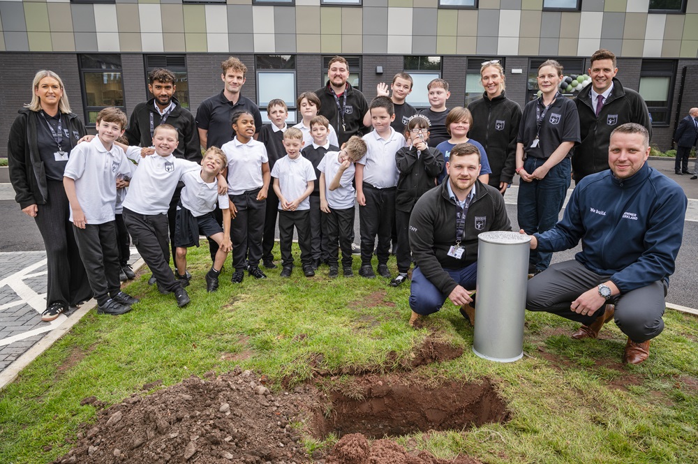 Teachers and pupils fill the time capsule ready for burial