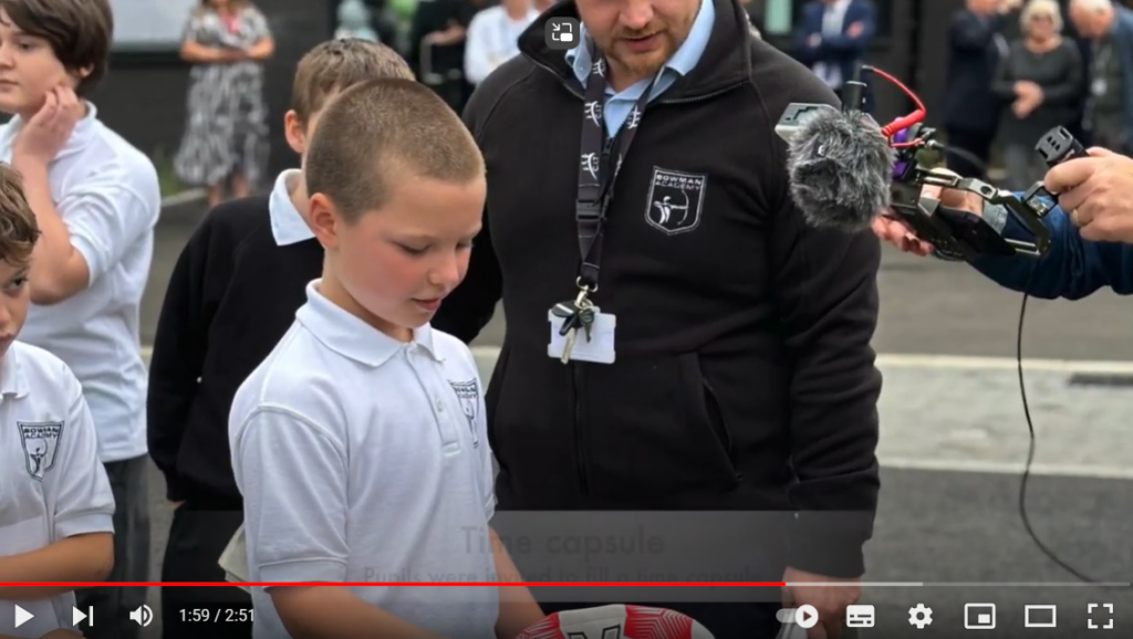 pupil and teacher put an item in the time capsule