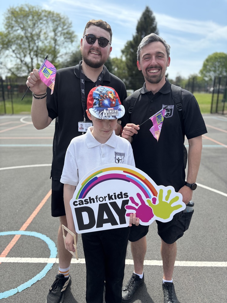 Staff and pupils holding a Cash for Kids sign